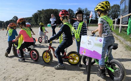 Kinder mit Helm sind mit dem Laufrad unterwegs